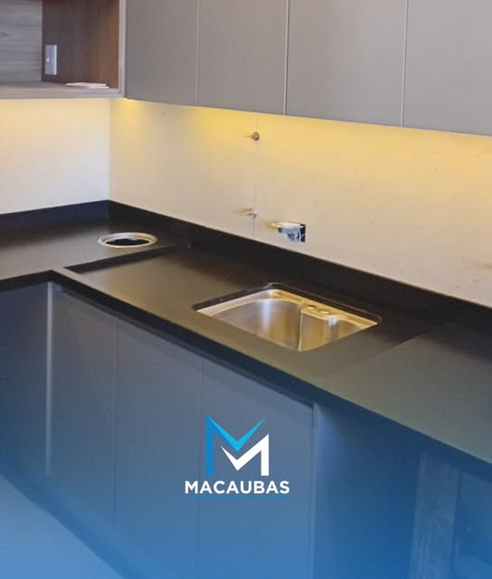 Bancada de cozinha em pedra escura com cuba de inox e recorte para cooktop