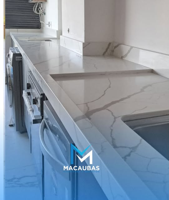 Bancada longa de cozinha em pedra clara com veios cinza